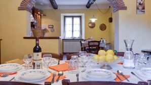 A dining area with a table set for four, a wine bottle, and a fruit bowl.