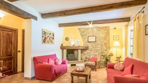 A cozy living room with a fireplace, red sofas, and a stone wall.