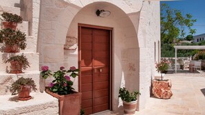 Un bâtiment en pierre avec une porte en bois, des plantes en pot et un ciel dégagé.