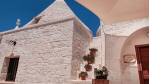 Un bâtiment en pierre blanche, surmonté d’un toit conique, agrémenté de plantes en pot et portant une enseigne indiquant « Furnace del Vicole ».