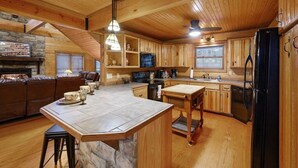 A spacious kitchen with wooden cabinets, a central island, and a stone accent wall.
