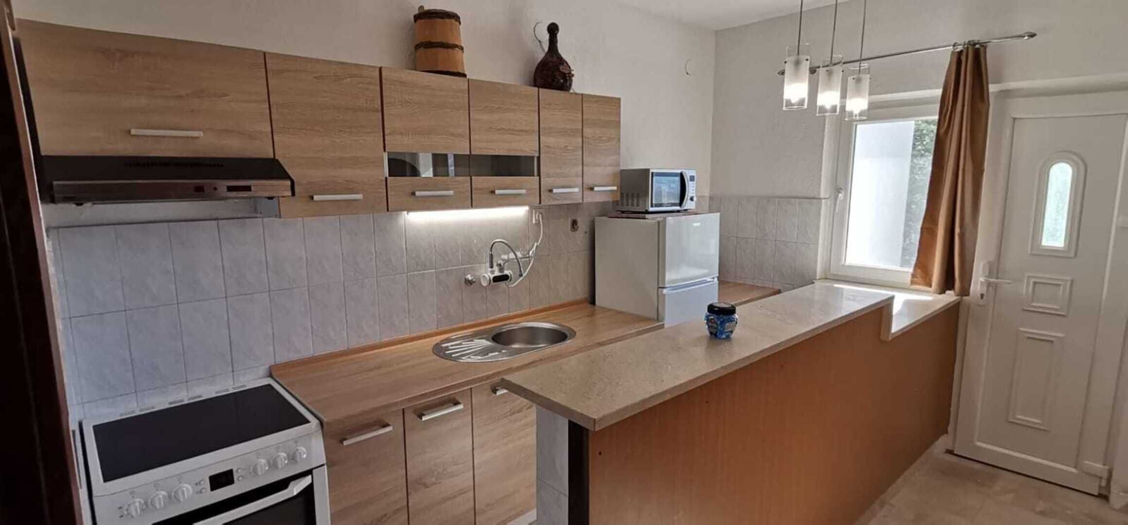 A modern kitchen with wooden cabinets, a built-in oven, a microwave, and a sink.
