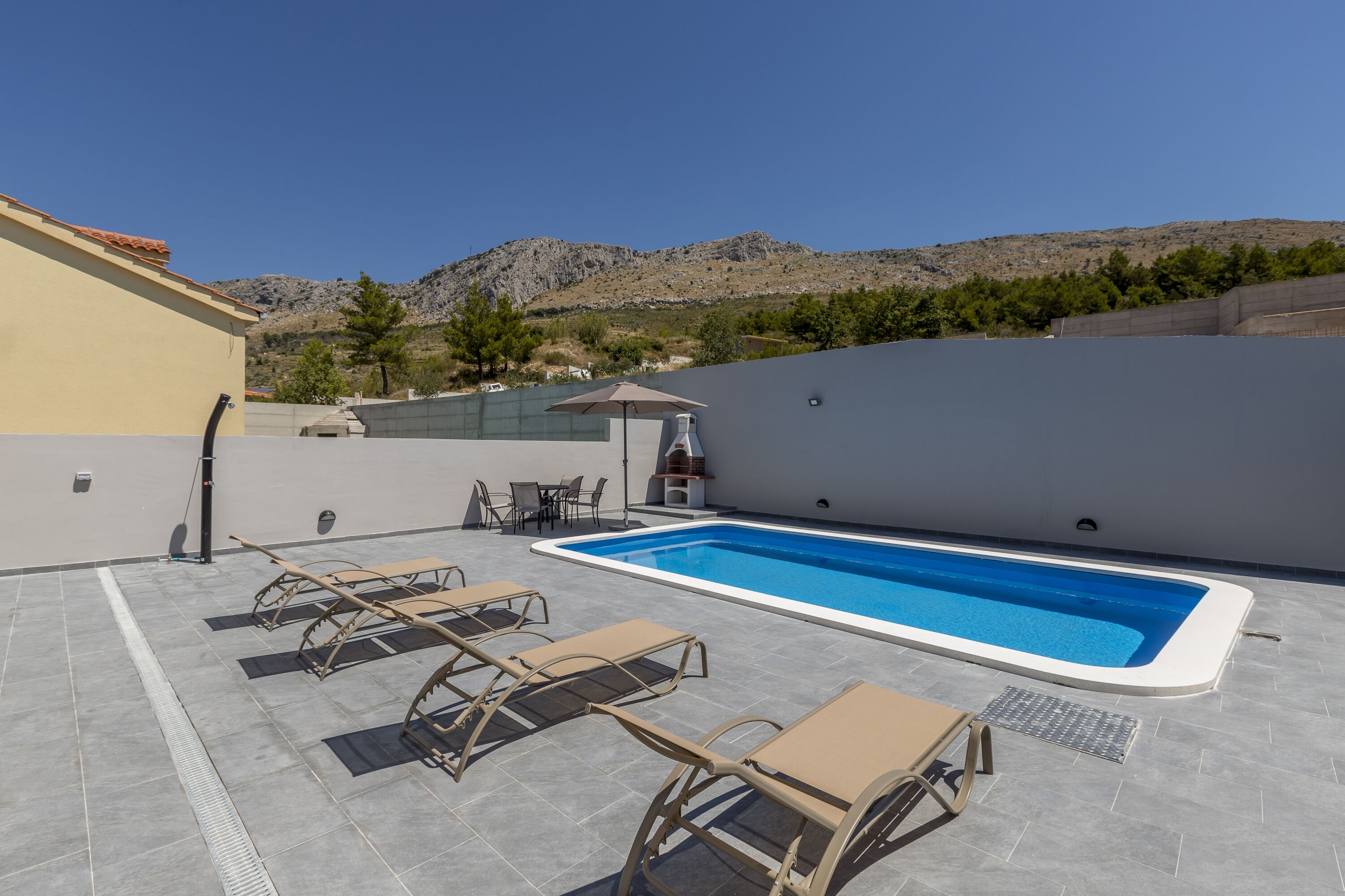 A rooftop pool area with lounge chairs and a barbecue setup.