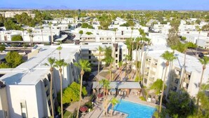 A hotel with a swimming pool surrounded by palm trees and a view of the cityscape.