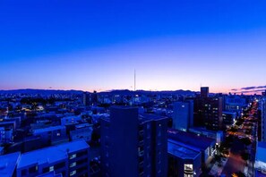 A cityscape at dusk with buildings and a prominent tower.