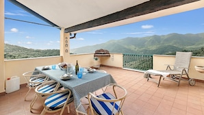 A balcony with a table set for dining, chairs, a grill, and a scenic mountain view. - Ca Veggia for Nature Lovers With Views & Garden (Stellanello)