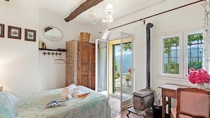 A bedroom with a bed, a wooden wardrobe, a window with a view, and a wooden table with a chair. - Ca Veggia for Nature Lovers With Views & Garden (Stellanello)