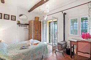 A bedroom with a bed, a wooden cabinet, a mirror, and a window with a view. - Ca Veggia for Nature Lovers (Stellanello)
