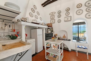 Una cocina con armarios blancos, un lavaplatos, un refrigerador y una ventana con vistas.