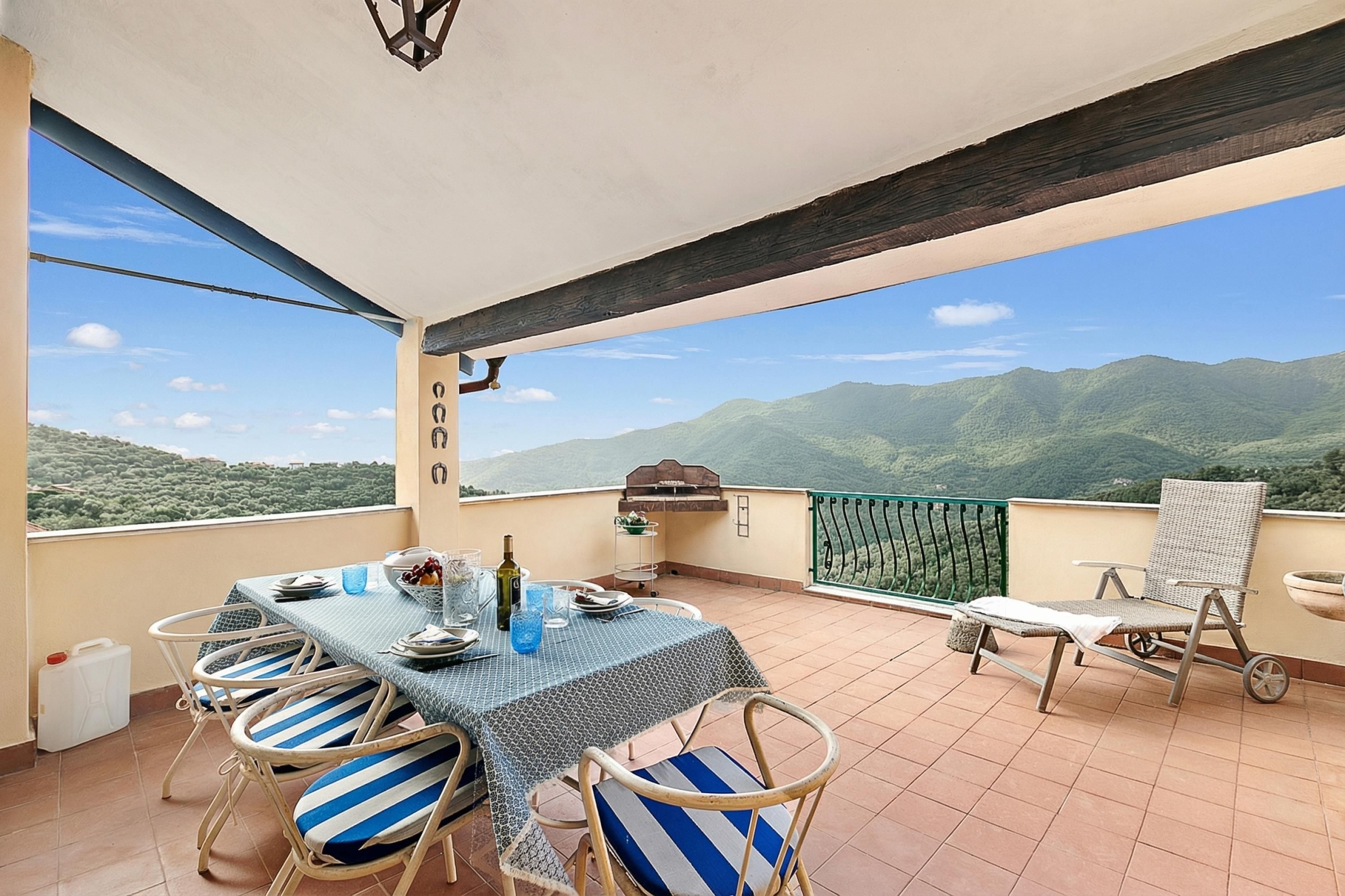 Un balcon avec une table dressée pour les repas, des chaises, un barbecue et une vue imprenable sur les montagnes.