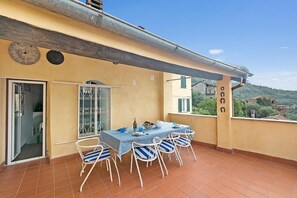 A balcony with a table set for four, chairs, a decorative metal gate, and a view of the surrounding area. - Ca Veggia for Nature Lovers With Views & Garden (Stellanello)