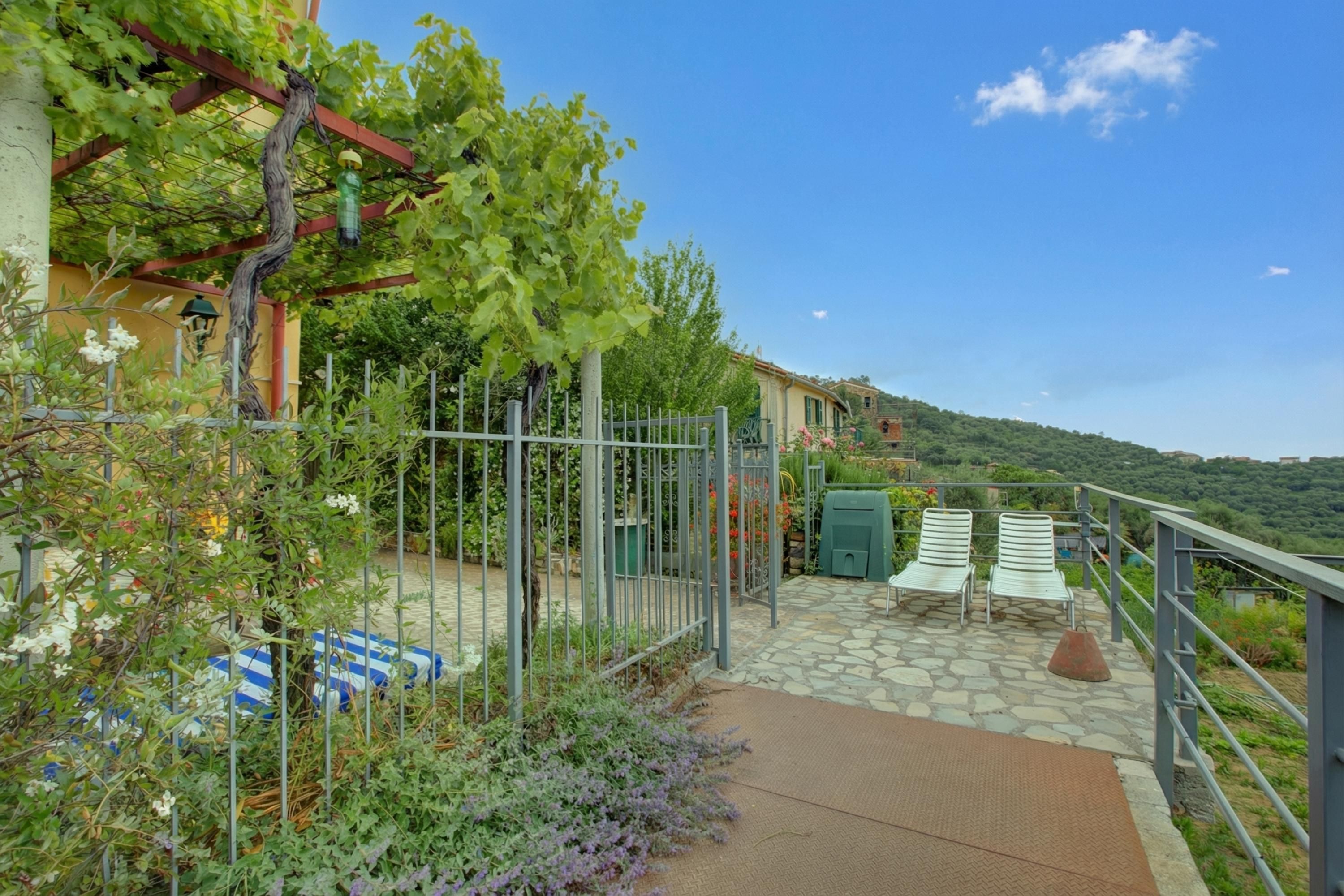 A garden with a pergola, a stone pathway, and outdoor seating.
