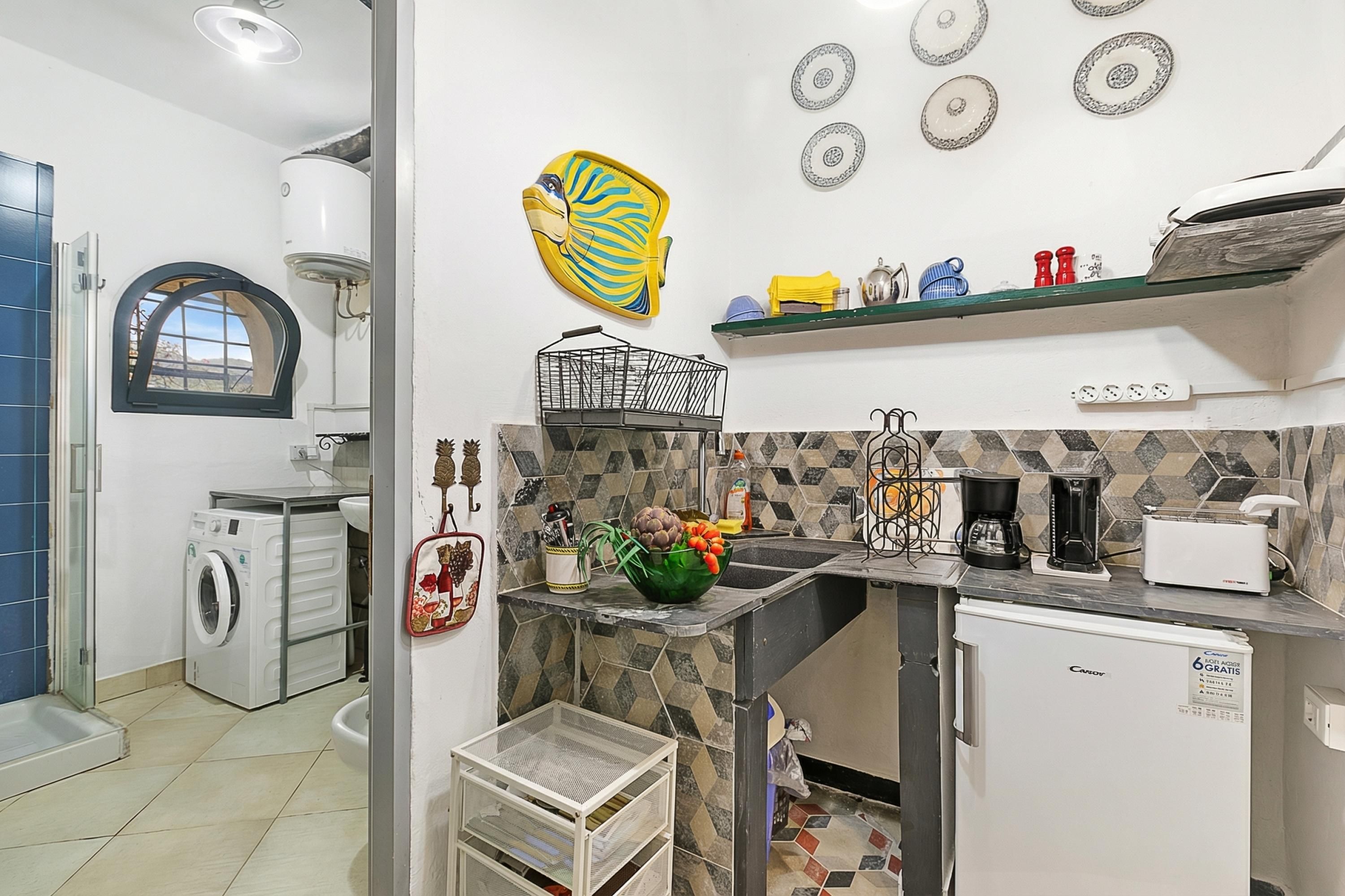 A compact kitchen with a washing machine, a sink, a coffee maker, and a refrigerator.
