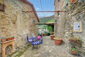 A stone courtyard with a table and chairs, potted plants, and a view of a hillside. - Ca Veggia for Nature Lovers With Views & Garden (Stellanello)