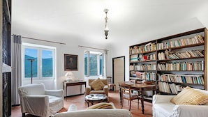 A living room with a large bookshelf, a fireplace, and a view of the outdoors. - Ca Veggia for Nature Lovers With Views & Garden (Stellanello)