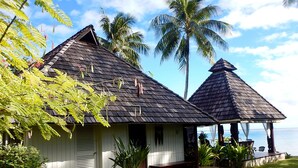 A two-story building with a dark shingled roof, a covered porch, and a view of the ocean. - Pension Poerani Moorea - DeLuxe Suite, living room, kitchen, 2 bedrooms a/c (Moorea)