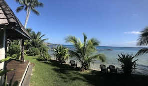 A beachfront property with a wooden deck, palm trees, and a view of the ocean.