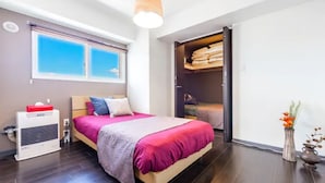 A modern bedroom with a bed, a heater, a wardrobe, and a window with blinds. - Diva (Sapporo)