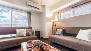 A modern hotel room with two sofas, a coffee table with a tray, and a standing lamp. - Diva (Sapporo)