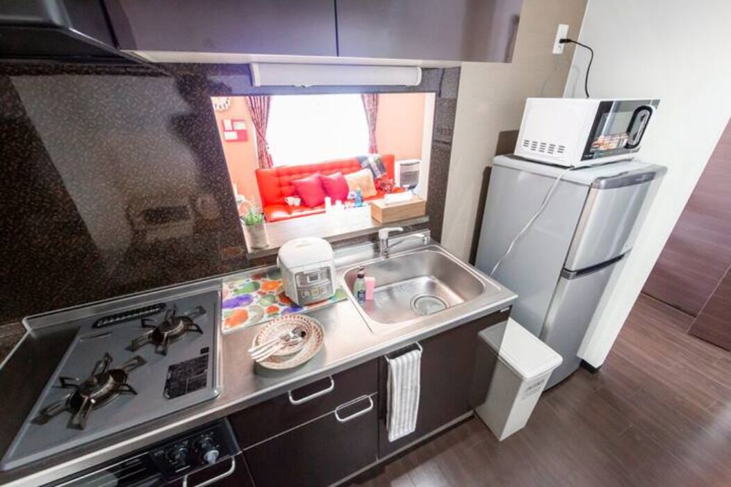 A compact kitchen with a gas stove, a microwave, and a refrigerator.