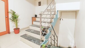 A staircase with metal railings, a potted plant, and a door. - Hotel 4 Seasons (Bhopal)