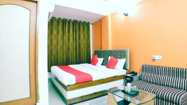 A hotel room with a bed, a sofa, a glass coffee table, a ceiling fan, and a window with curtains. - Hotel 4 Seasons (Bhopal)