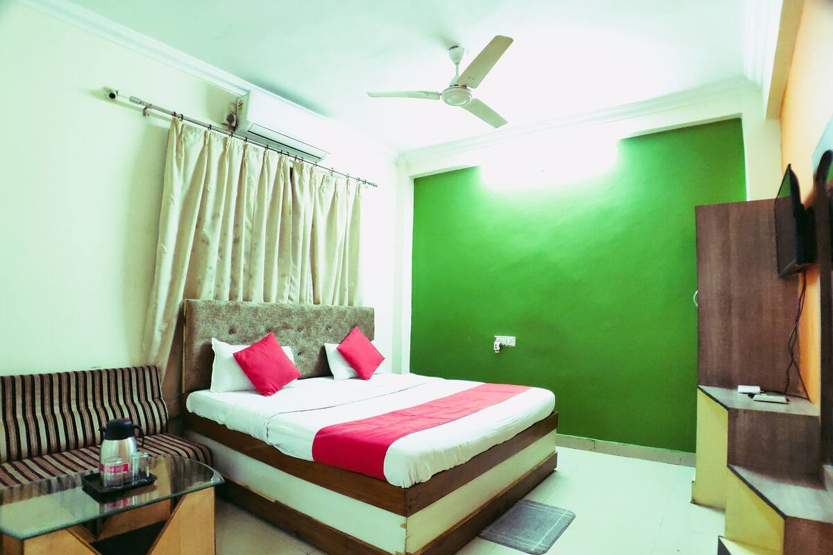 A hotel room with a bed, a sofa, a coffee table, a television, and a ceiling fan.