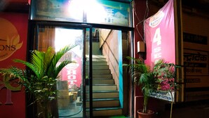A hotel entrance with a staircase leading inside, potted plants in front, and a sign indicating the establishment is open. - Hotel 4 Seasons (Bhopal)
