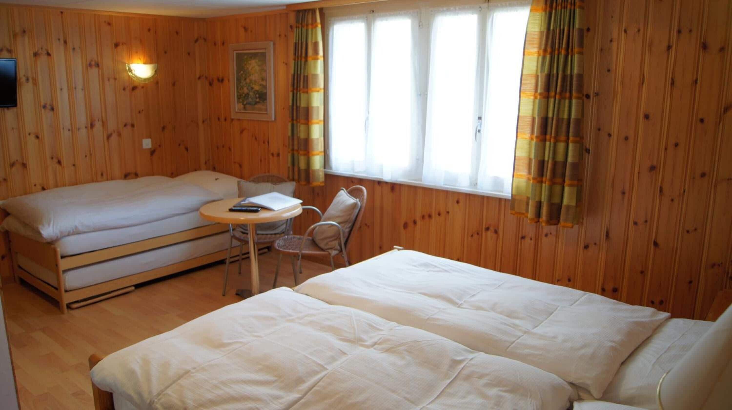 Una habitación con dos camas, una mesita y una silla.