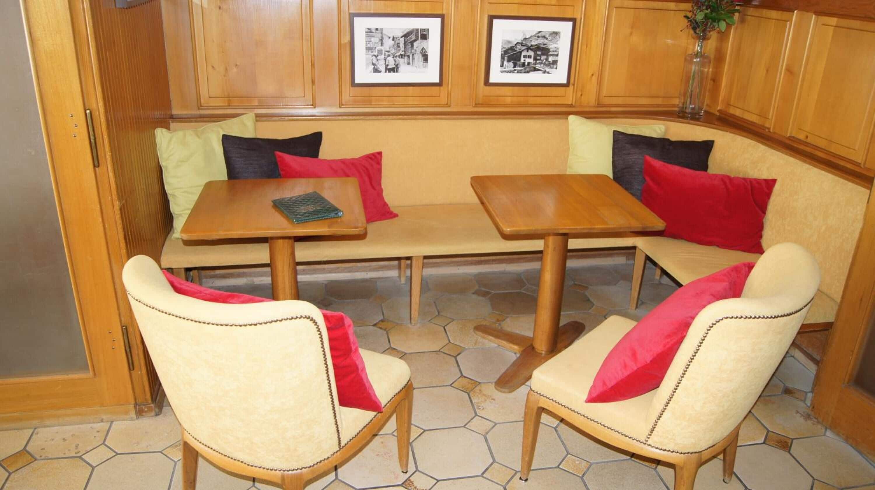 A cozy seating area with a wooden bench and two chairs, a small table, and a tiled floor.