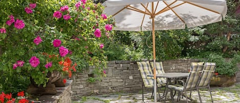 A patio with stone flooring, a table with chairs, and a large umbrella.
