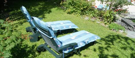 Two outdoor lounge chairs with blue cushions in a grassy garden area.