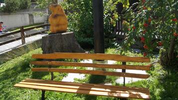 Un banco de madera con una escultura de oso tallado en un tocón de árbol en un parque.