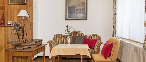 Una habitación acogedora con una mesa de madera, un sofá, un radiador y un cuadro enmarcado en la pared.