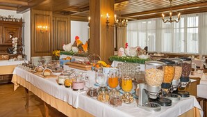 Una mesa de buffet con diversos alimentos y bebidas, paneles de madera y una araña.