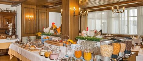A buffet setup with various food items and beverages, wooden paneling, and a chandelier.