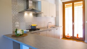 Une cuisine moderne équipée d’une cuisinière à gaz, d’un four encastré et d’une hotte en acier inoxydable. On y trouve un évier avec un robinet, ainsi qu’une fenêtre avec des rideaux.