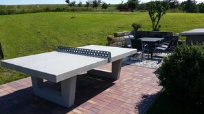 Eine Terrassenausstattung mit einem Betontisch und Stühlen, umgeben von einem Pflasterweg und einer Rasenfläche.