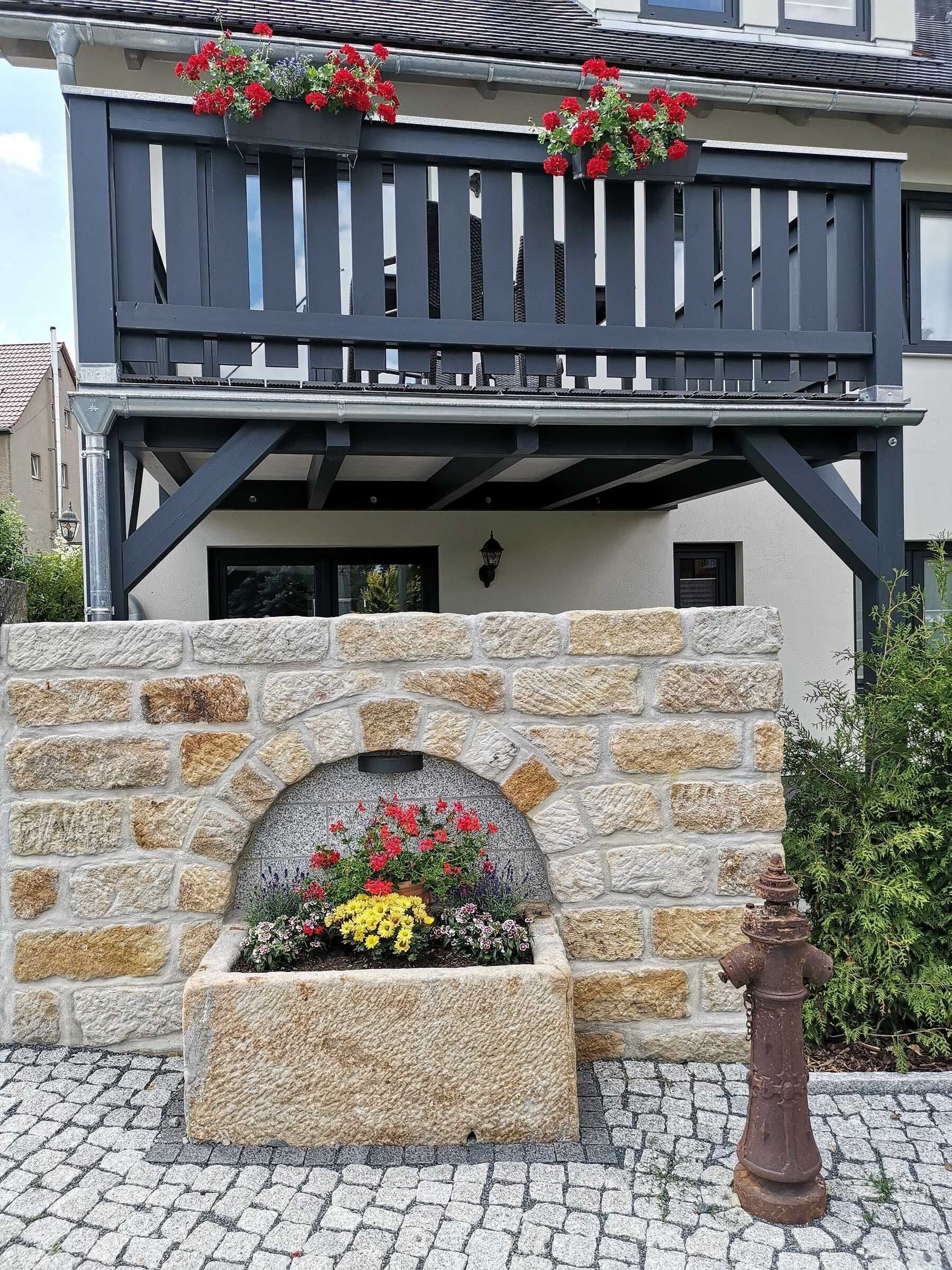 Ein Gebäude mit einer Stein-Fassade, einem Balkon mit Blumenkästen und einem Hydranten.