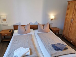 Ein Doppelbett mit zwei Nachttischen, einem Holzschrank und einer Steckdose.