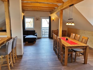 Acogedor loft con comedor, vigas de madera y vista por un ventanal amplio.