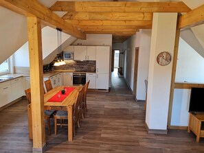Una cocina moderna con armarios blancos, una mesa de comedor de madera y un mantel individual rojo.