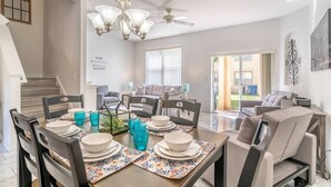 A dining area with a chandelier, a ceiling fan, and a wall with a motivational quote.