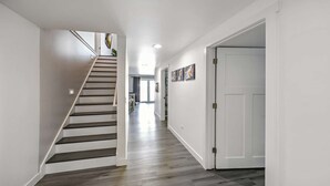 Un intérieur moderne avec un escalier, un couloir et une porte.