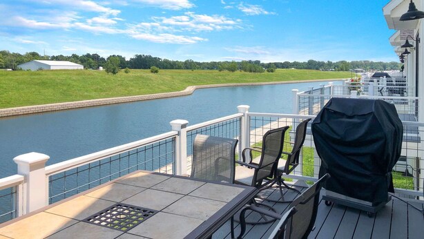 Une terrasse avec vue sur une rivière, un espace salon extérieur et un barbecue.