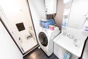 A compact laundry room with a washing machine, a dryer, and a sink. - Tender (Sapporo)