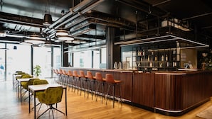 A modern bar area with a wooden counter and multiple stools. - Apartment Flamengo mit Küchenzeile - Rioca Vienna Posto 1 (Wien)