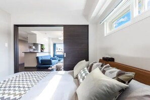A modern hotel room with a bed, a sofa, and a view of the living area. - Stardust (Sapporo)
