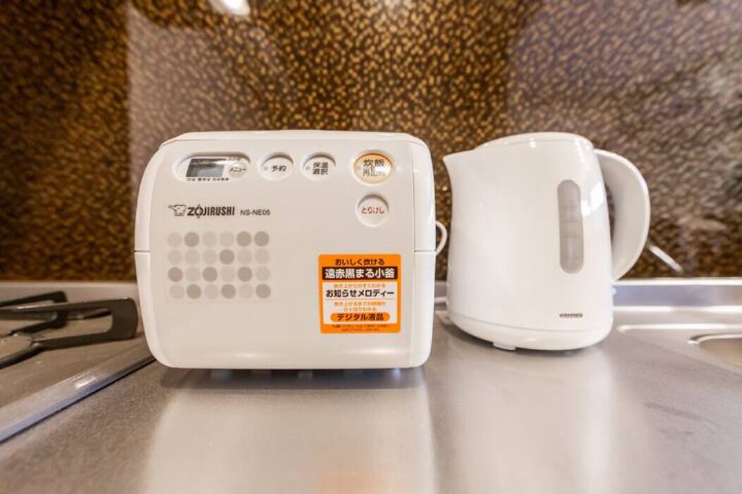 A white electric kettle and a white coffee maker on a kitchen counter.