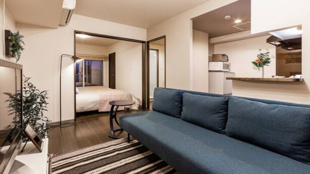 Un espace de vie compact comprenant un canapé, une petite table, un lit et une kitchenette.